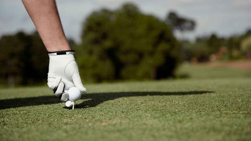 person puts ball on tee