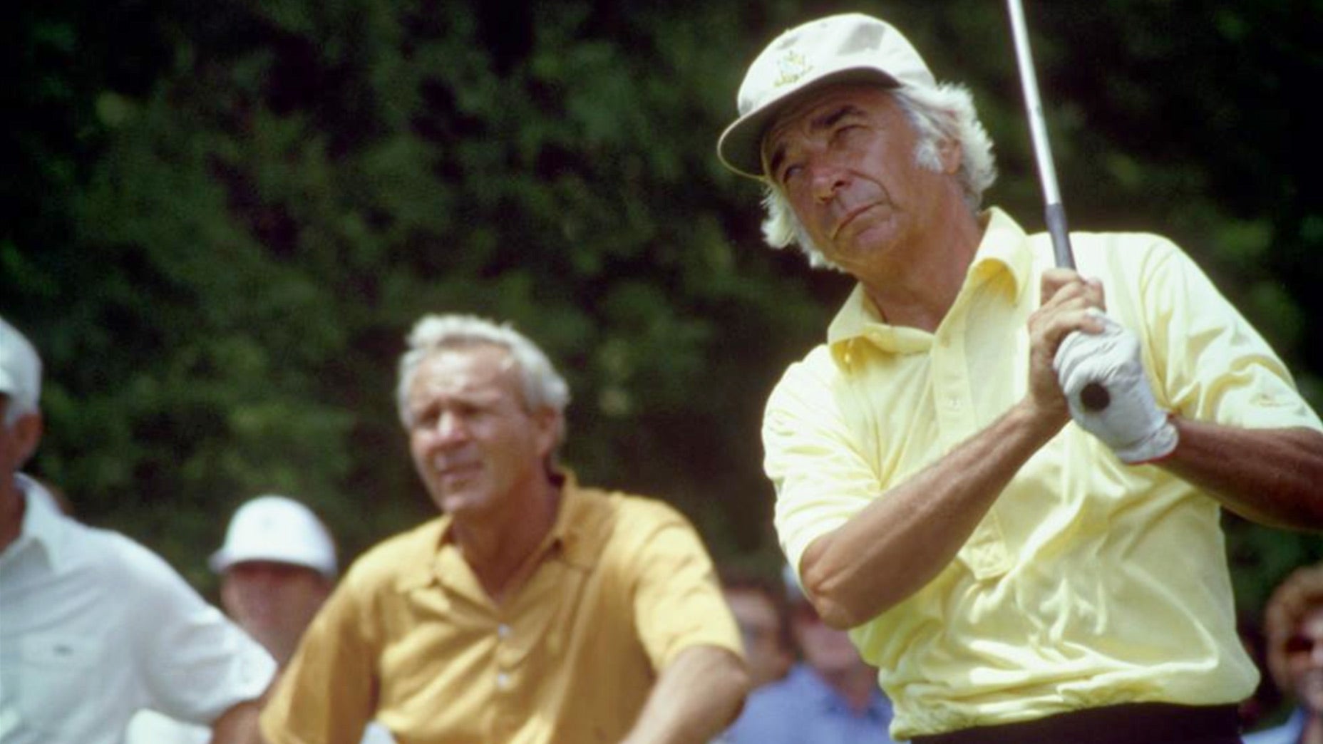 Bud Chapman tees off as Arnold Palmer looks on.