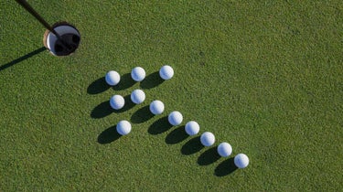 golf balls in arrow formation on green