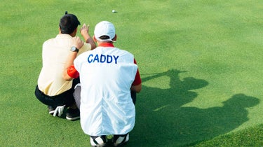 A golfer and caddie read a putt.