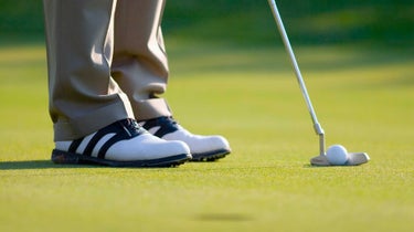 golfer lines up putter behind ball