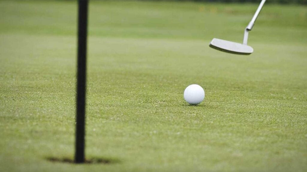 a golfer rolls a putt on a golf green