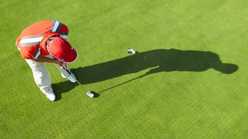 A golfer hits a short putt.